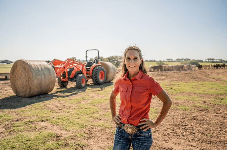 Woman standing in front of her tractor and hay bales